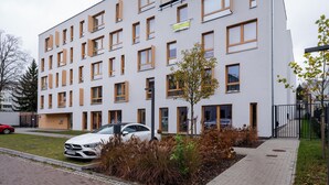 A modern multi-story building with a flat facade, numerous windows, and a gated entrance. - Platon 46 Modern Studio (Łódź)
