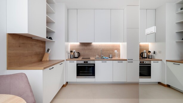 Una cocina moderna con armarios blancos, encimeras de madera y electrodomésticos integrados.