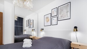 Un dormitorio moderno con una cama grande, una mesita de noche, un espejo y obras de arte en la pared.