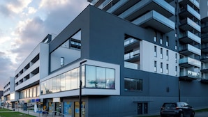 Un edificio moderno de varios pisos con techo plano, ventanas grandes y balcones.