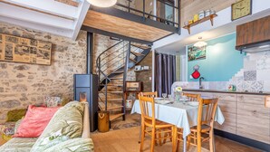A cozy interior with a dining area, a staircase, and a kitchen. - Holiday Home 'L'étable 15kms Puy Du Fou' with Private Terrace and Wi-Fi (Pouzauges)