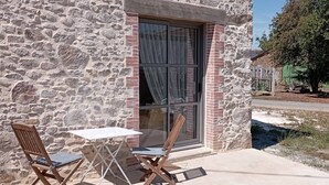 A stone building with a window, two wooden chairs, and a small table.