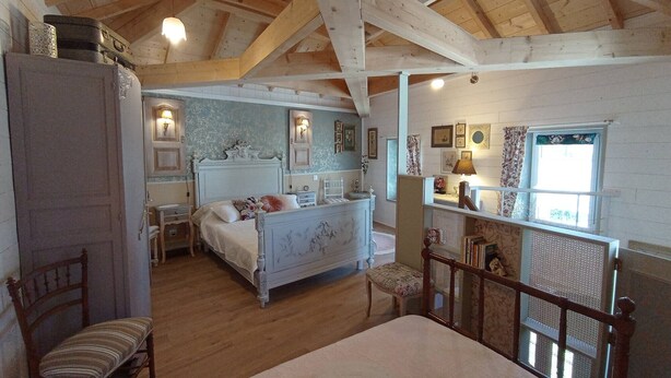 A bedroom with a wooden ceiling, a bed, a chair, a nightstand, and a dresser.