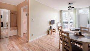 A modern living room with a dining area, a TV, and a large window with a view of the outside.