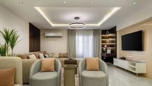 Ein modernes Wohnzimmer mit einer Sofagarnitur, zwei Sesseln, einem Couchtisch, einem Fernseher und einer eingebauten Unterhaltungseinheit.