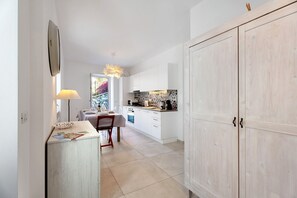 Une cuisine moderne avec des meubles blancs, un coin repas comprenant une table et des chaises, et une grande armoire.