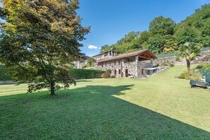A stone building with a balcony, surrounded by a well-maintained lawn and trees. - Holiday Home 'Residenza Jasmine Grey Apartment' with Private Garden and Wi-Fi (Verbania)