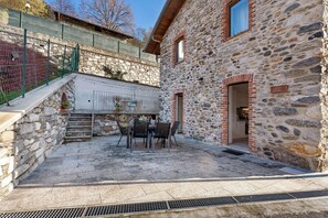 A stone building with a dining area featuring a table and chairs. - Holiday Home 'Residenza Jasmine Grey Apartment' with Private Garden and Wi-Fi (Verbania)