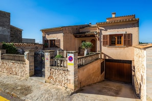 A two-story building with a stone facade, a gated entrance, and a clear blue sky.
