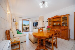 A spacious living area with a wooden dining table, a sofa, and a television.