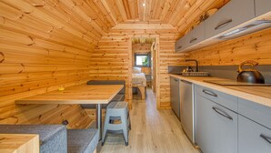 A wooden cabin interior with a kitchen, dining area, and a sleeping area. - Ôtonneauxstress – Beach Attendant: Unique Experience Just Steps from the Atlantic (Saint-Vivien-de-Médoc)