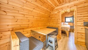 A wooden cabin interior with a bed, a table, and a bench. - Ôtonneauxstress – Beach Attendant: Unique Experience Just Steps from the Atlantic (Saint-Vivien-de-Médoc)