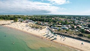 Vista aérea de una zona costera con playa, un pueblo pequeño y cielo despejado.