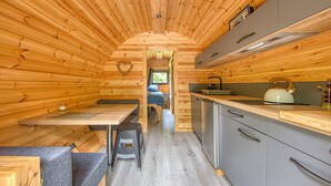 Interior acogedor de una cabaña de madera con kitchenette, comedor y zona de descanso.