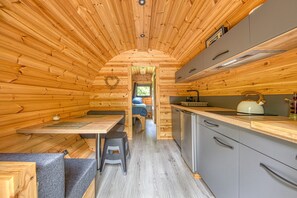 A compact wooden cabin interior with a kitchenette, a dining area, and a sleeping space. - Ôtonneauxstress – Le Pêcheur: Relaxation and Nature in the Médoc, Close to the Ocean (Saint-Vivien-de-Médoc)