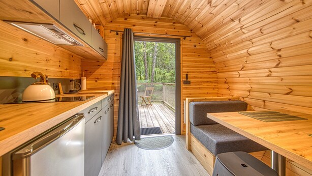 Una cabaña compacta con kitchenette, comedor y vistas al exterior.