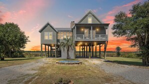 A two-story house with a balcony, a small pool, and a gravel driveway. - The Cajun Cottage - Private Boat Launch/Dock (Ocean Springs)