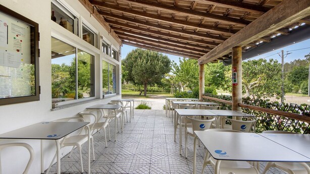 An outdoor cafe with tables and chairs, a wooden ceiling, and a view of trees and greenery. - Room 'Quarto 5 - Jorge Galinheiro' with Mountain View, Shared Garden and Wi-Fi (Mamouros)