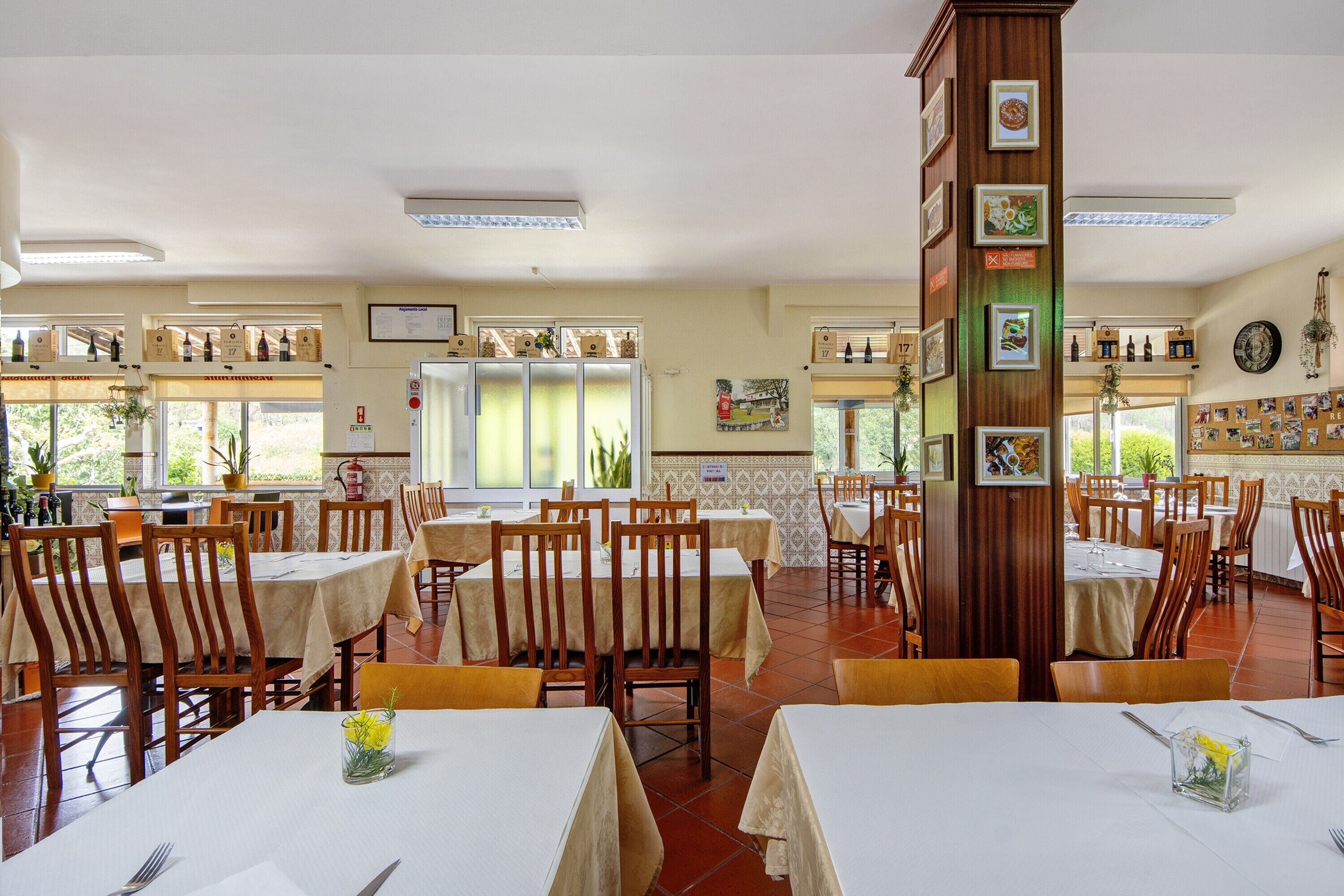 Un restaurant amb diverses taules i cadires, un piló alt amb quadres emmarcades, i vista cap a l'exterior.