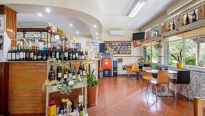 A bar area with shelves of wine bottles, a cash register, and a seating area with chairs and tables. - Room 'Quarto 5 - Jorge Galinheiro' with Mountain View, Shared Garden and Wi-Fi (Mamouros)