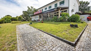 A building with a paved entrance, a signboard, and a well-maintained lawn. - Room 'Quarto 5 - Jorge Galinheiro' with Mountain View, Shared Garden and Wi-Fi (Mamouros)