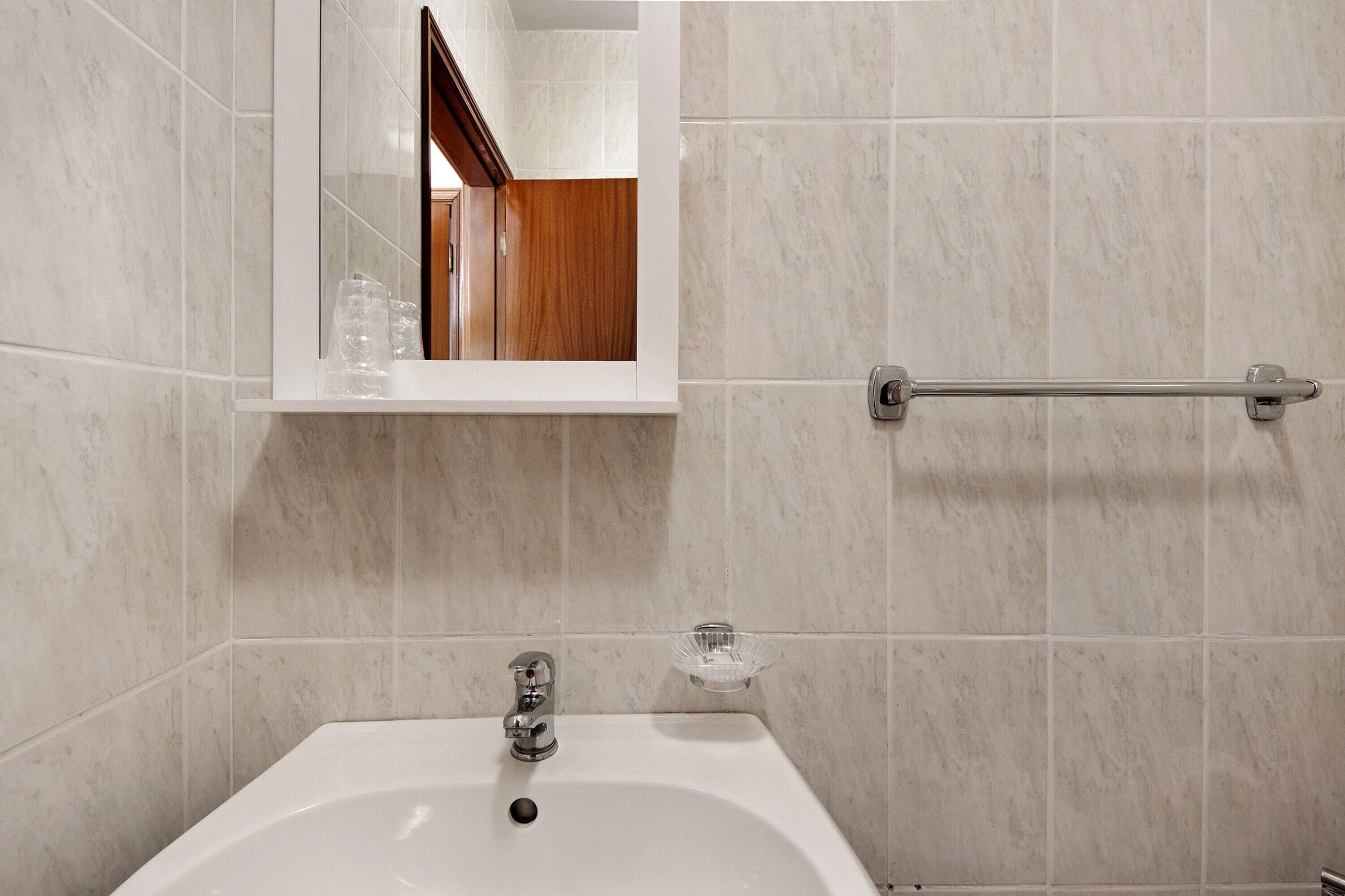 A bathroom with a white sink, a mirror, and a towel rack.