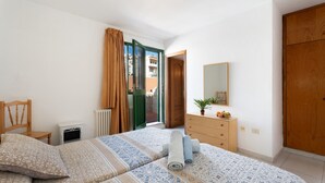 A bedroom with a bed, a dresser, a chair, a radiator, and a door leading to a balcony. - 'Habitación 12 Con Balcón' with Balcony and Wi-Fi (Vilaflor)