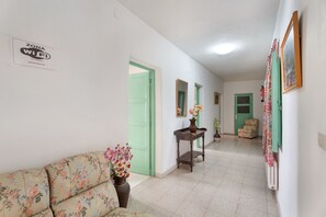 Un couloir avec un canapé, une table sur laquelle est posé un vase et une chaise.
