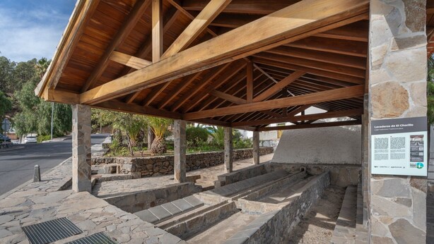 Une construction en pierre surmontée d’un toit en bois, avec des marches en pierre et une enseigne.