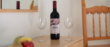 Una botella de vino, dos copas y una silla de madera sobre una mesa.