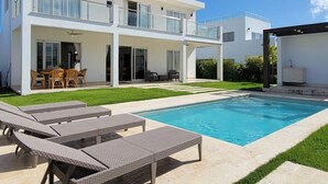 Une maison moderne à deux étages, dotée d’une piscine, de mobilier d’extérieur et d’une pelouse bien entretenue.
