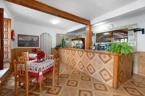 Un restaurant avec un comptoir en bois, un sapin de Noël et une table recouverte d’une nappe rouge.