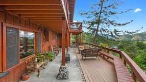 A wooden deck with outdoor seating, a view of the landscape, and a covered area with windows. - No Cleaning Fee ~ Awesome Views~8Beds~Near Restaurants & Sequoia Park (Three Rivers)