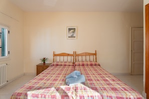 Une chambre à coucher avec un lit, une table de chevet, une plante en pot et un tableau encadré au mur.