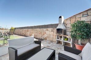 An outdoor patio with wicker furniture, a stone wall, a barbecue grill, and potted plants. - 'Marcela Joaquin  Mountain House' with Sea View, Private Pool and Wi-Fi (Fasnia)