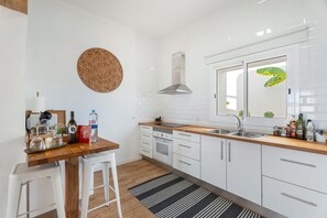 Et moderne køkken med hvide skabe, en træbordplade og en rustfri stålvask.