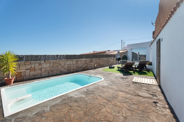 A swimming pool with stone flooring, a patio with outdoor furniture, and a stone wall. - 'Marcela Joaquin  Mountain House' with Sea View, Private Pool and Wi-Fi (Fasnia)