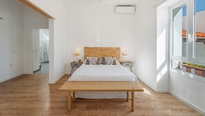 A bedroom with a wooden headboard, a large bed, bedside tables with lamps, a bench, and a window with a view. - 'Marcela Joaquin  Mountain House' with Sea View, Private Pool and Wi-Fi (Fasnia)