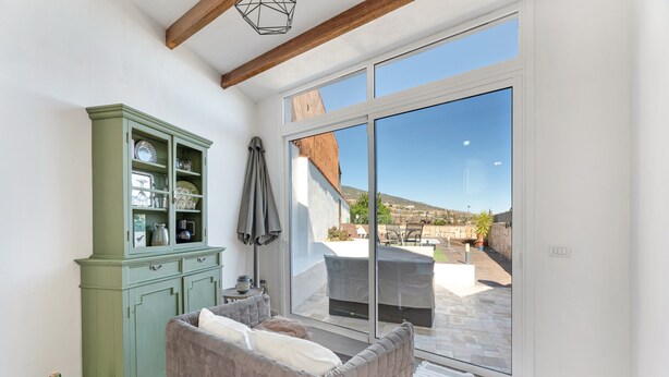 A room with a green cabinet, a grey sofa, and a large sliding glass door leading to an outdoor patio. - 'Marcela Joaquin  Mountain House' with Sea View, Private Pool and Wi-Fi (Fasnia)