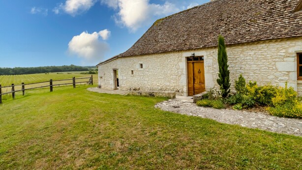 A stone farmhouse with a wooden door, a stone pathway, and a fenced field in the background. - Chez Jacquou – Authentic Charm and Modern Comfort with Private Pool in the Heart of Périgord (Bouniagues)