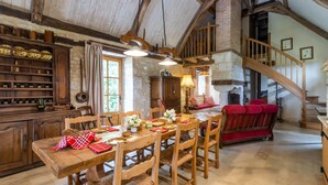 A rustic dining area with wooden furniture, a staircase, and a stone wall. - Chez Jacquou – Authentic Charm and Modern Comfort with Private Pool in the Heart of Périgord (Bouniagues)