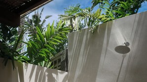 Un espace douche moderne avec un mur en béton, une petite fenêtre et un robinet.