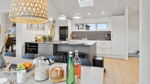 Una cocina moderna con una isla central, iluminación colgante y tragaluces.