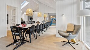 Un comedor moderno con una mesa larga, sillas negras y luces colgantes.
