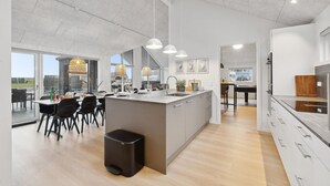 Una cocina moderna con una isla central, iluminación colgante y vistas al exterior.