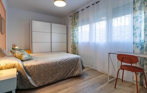 Cozy retreat with a neatly made bed and a dedicated workspace.