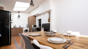 Una cocina moderna con una mesa de comedor de madera para dos personas, un refrigerador negro y una lavadora.
