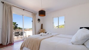 Un dormitorio con una cama grande, vistas al exterior y una lámpara en el techo.