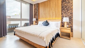 Ein modernes Schlafzimmer mit einem großen Bett, einem Holz-Kopfteil und Blick auf einen Balkon.