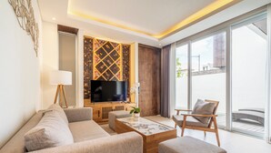 Ein modernes Wohnzimmer mit Sofa, Sessel, Couchtisch und Fernseher.